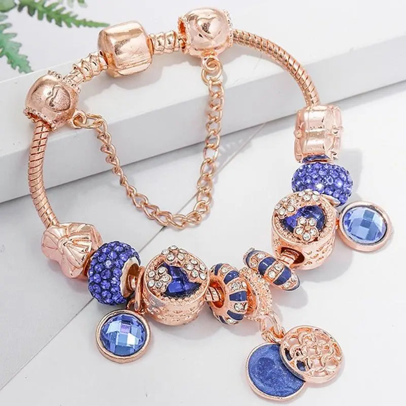 Roséfarbenes Charm-Armband mit funkelnden blauen Kristall-Anhängern